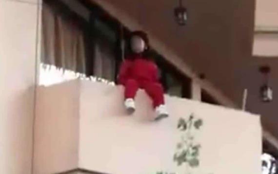 Dejan sola a niña en su casa y sale al balcón del edificio; la rescatan de caer
