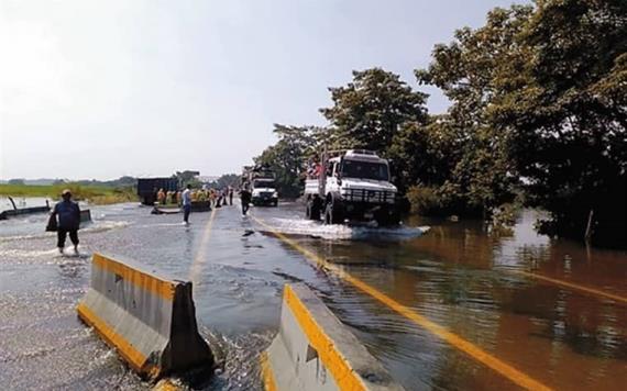 Ante cierre de carretera, trepan camiones para cruzar vado