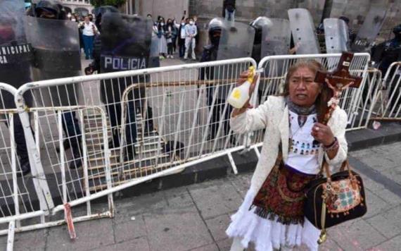 Mujer con crucifijo en mano rocía agua bendita a feministas durante marcha