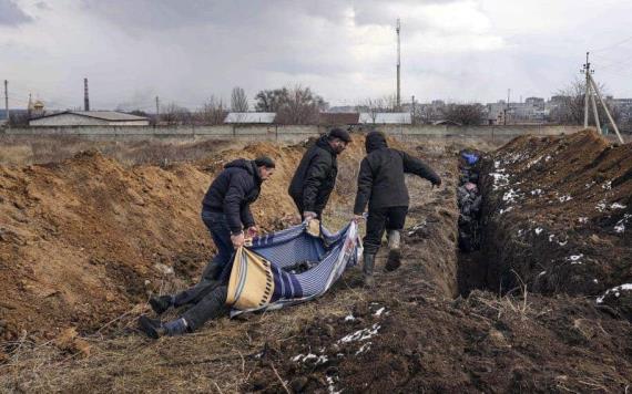 Cadáveres de niños yacen en una fosa larga y estrecha cavada a los apurones en Mariúpol