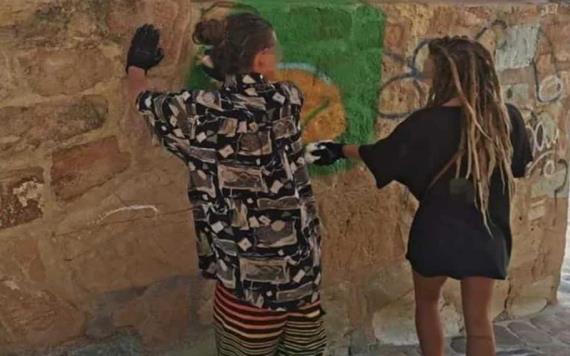 Pareja de estadounidenses son detenidos tras grafitear un acueducto histórico en Oaxaca; los ponen a despintar